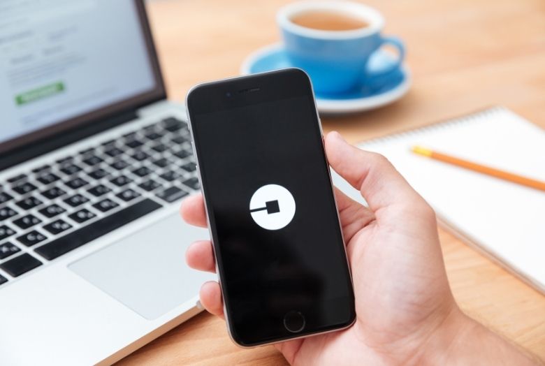mão segurando um celular com o símbolo da uber na tela