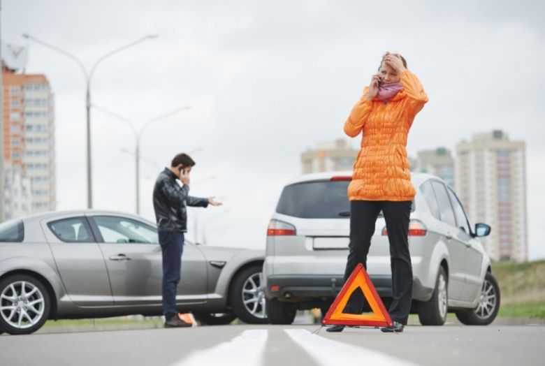 acidente de carro com duas pessoas falando ao telefone acionando o seguro