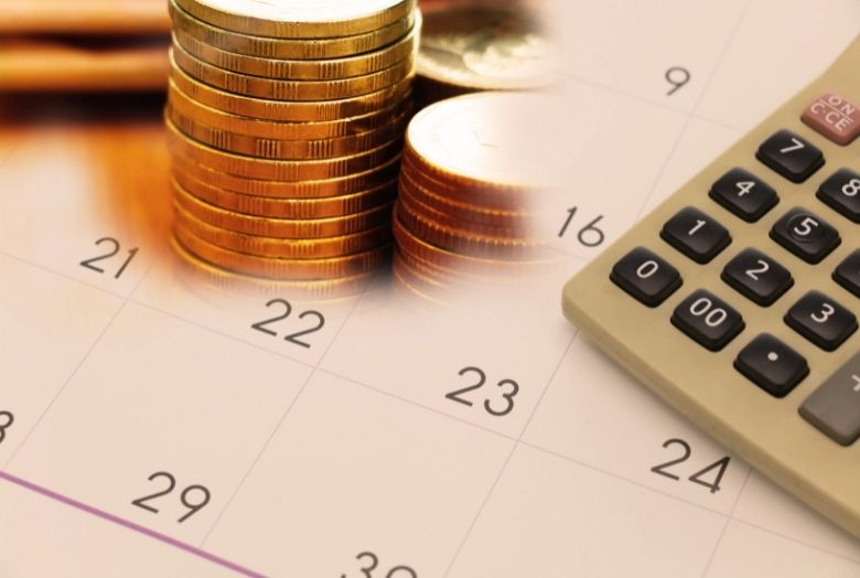 calendário com moedas e calculadora em cima