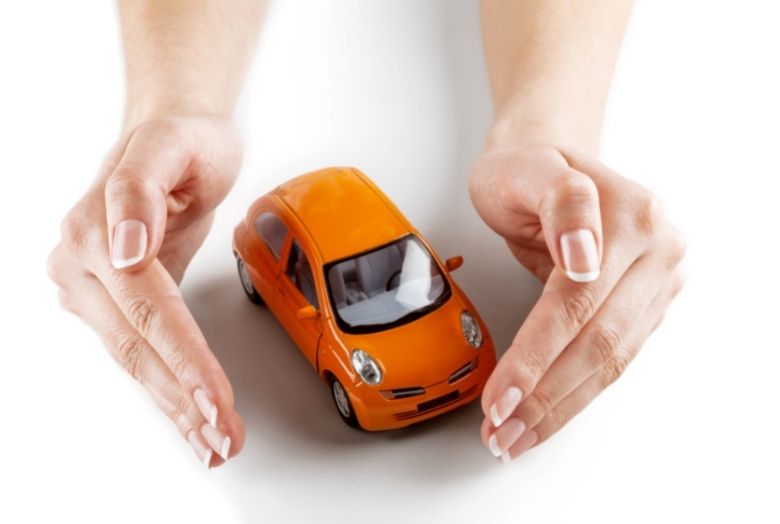 um par de mão fazendo um cerca ao redor de um carro laranjado em miniatura