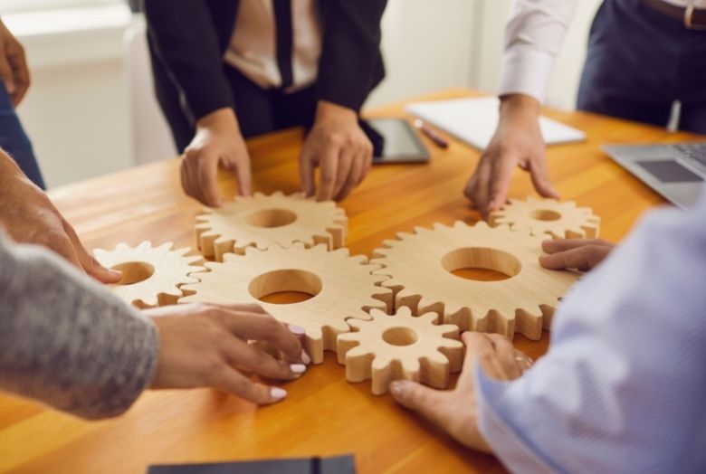 Um grupo de pessoas encaixando engrenagens em cima de uma mesa